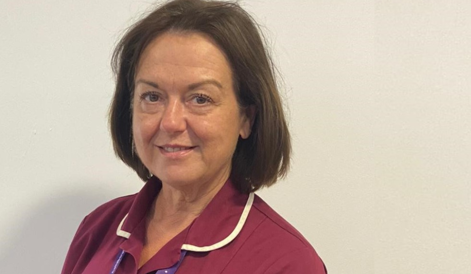 Person stares to the camera and smiles in red uniform against a white background.