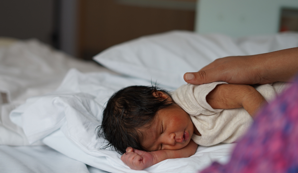 Mother holds baby whilst the baby is sleeping.