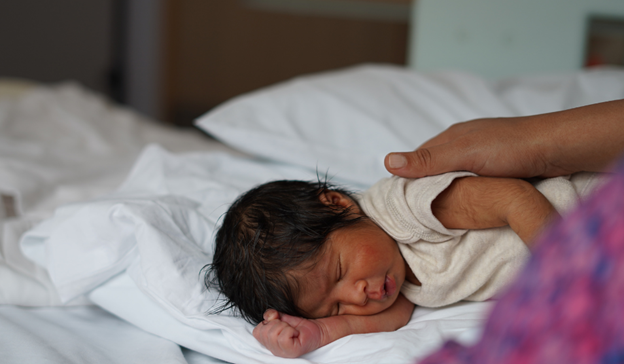 Mother holds baby whilst the baby is sleeping.