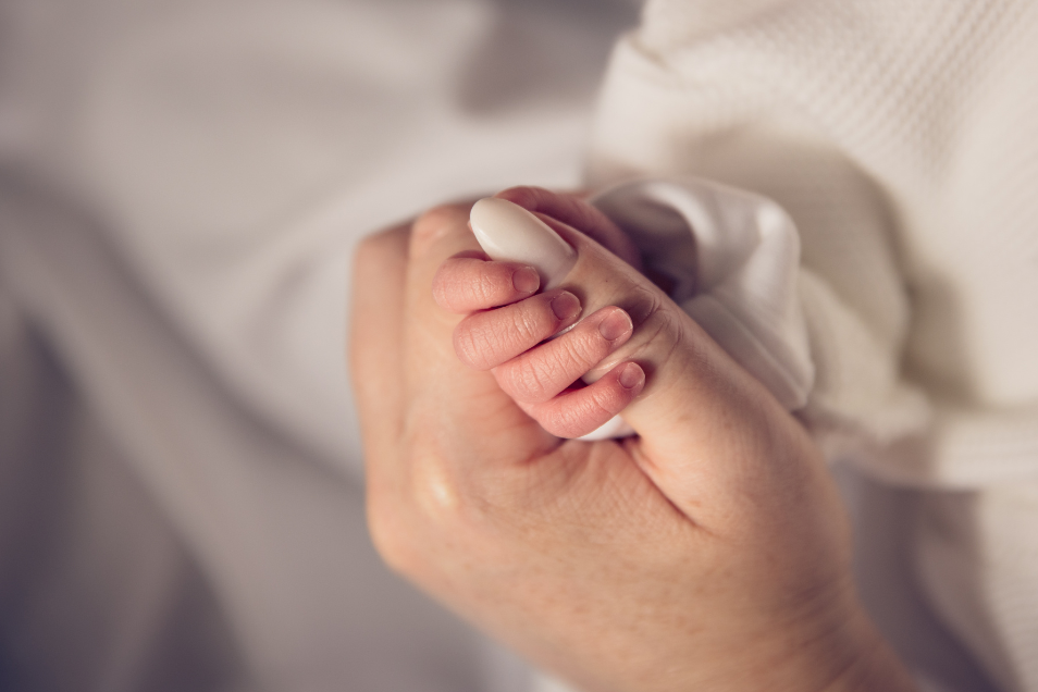Baby wraps hand around adult hand
